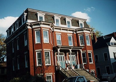 A red brick building with a blue car parked in front.