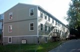 A grey building with a white door and windows.