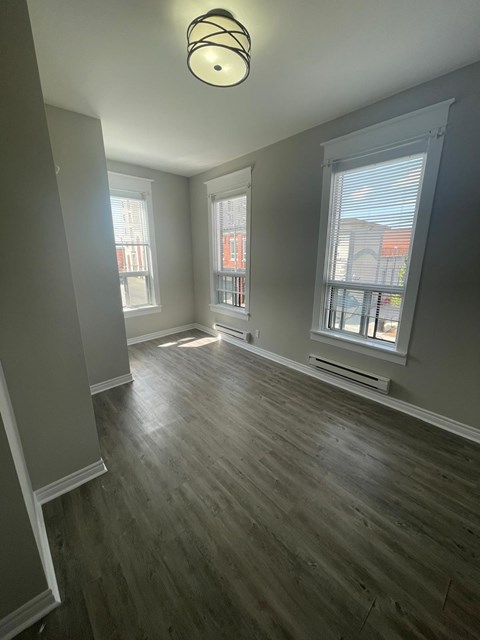 A room with wooden floors and a window overlooking a cityscape.