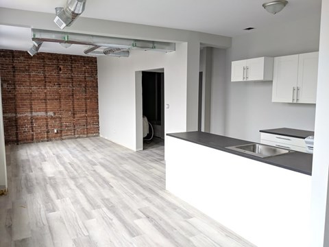 A kitchen with a brick wall and white cabinets.