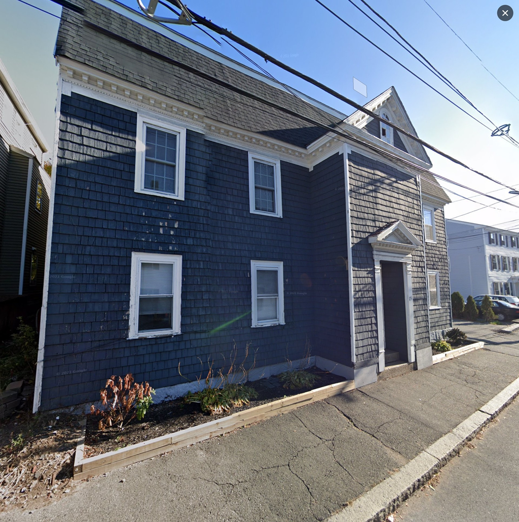 A blue house with white trim and a grey roof.