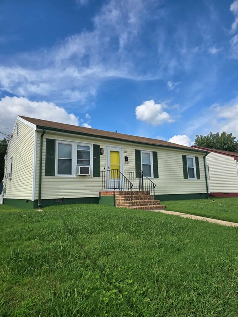 A small house with a yellow door and a red roof.