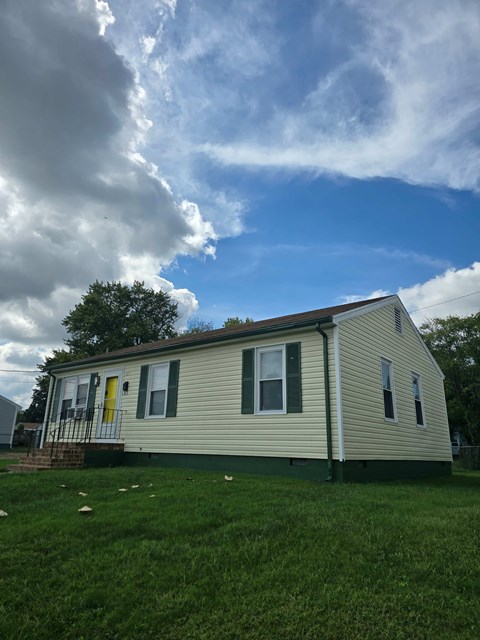 A house with a green lawn and a yellow door.