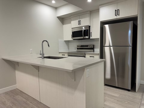 A modern kitchen with a stainless steel refrigerator and a white countertop.