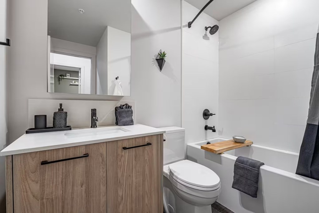 A white bathroom with a toilet, sink, and a mirror.