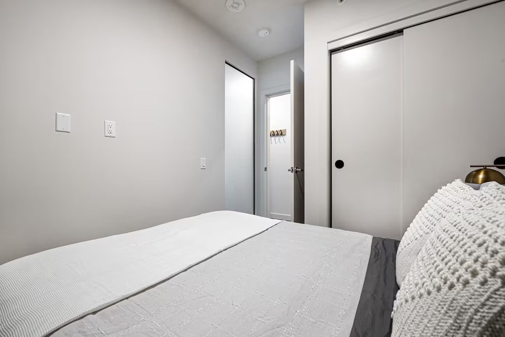 A white bed in a room with a white door.