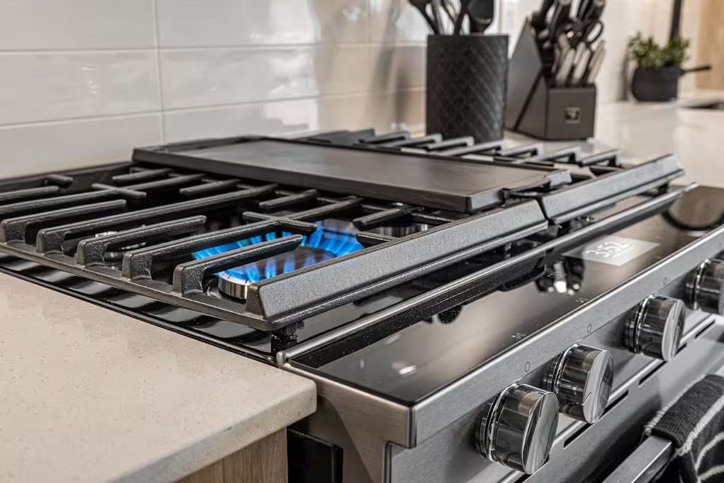A modern gas stove with blue flames in a kitchen.