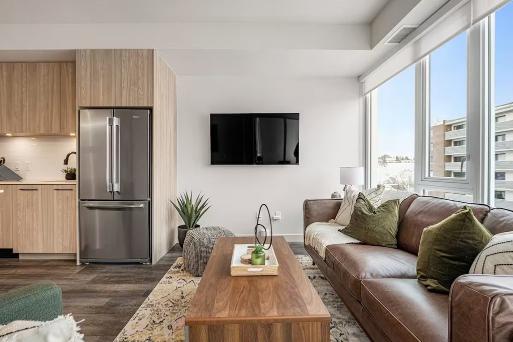 A modern living room with a brown leather couch and a wooden coffee table.