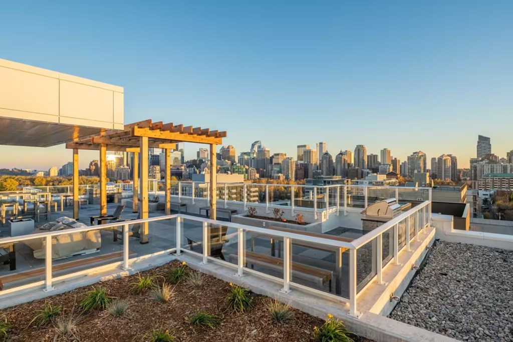 A rooftop patio with a view of the city skyline at dusk.