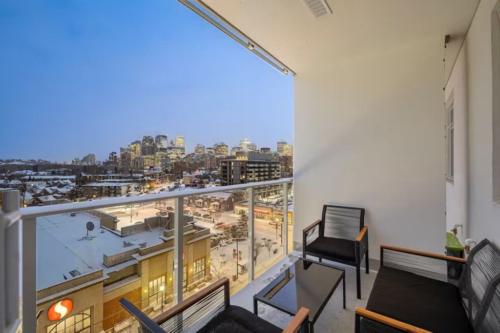 A balcony with a table and chairs overlooking a cityscape.