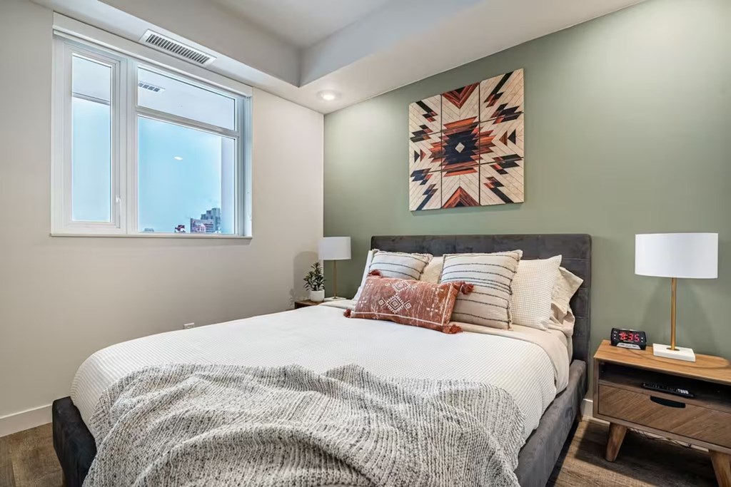 A bedroom with a large bed and a colorful artwork on the wall.
