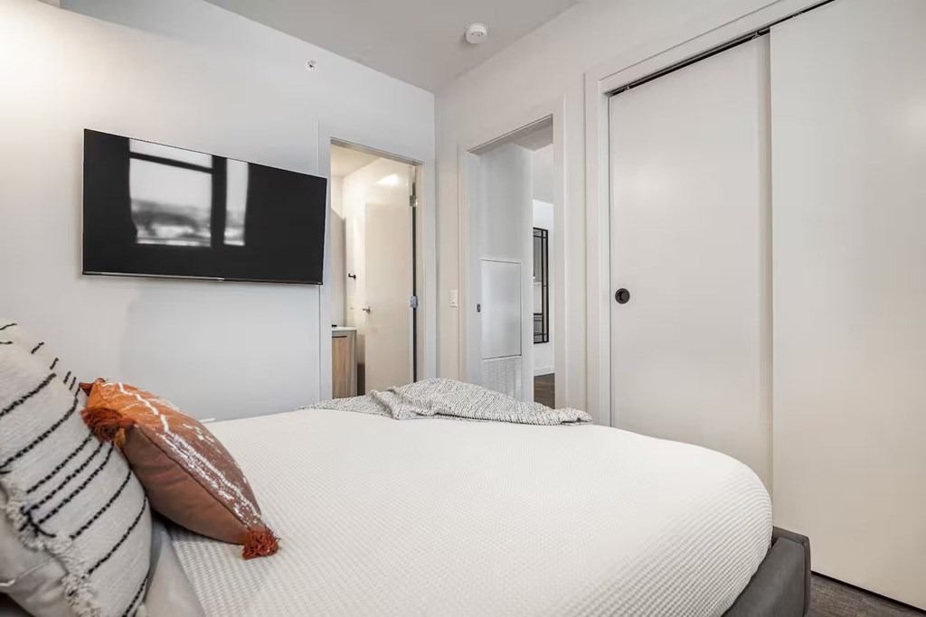 A bedroom with a large bed and a flat screen TV mounted on the wall.