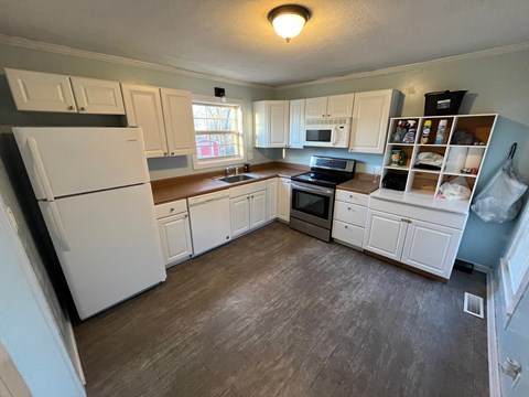 A kitchen with white cabinets and a white fridge.