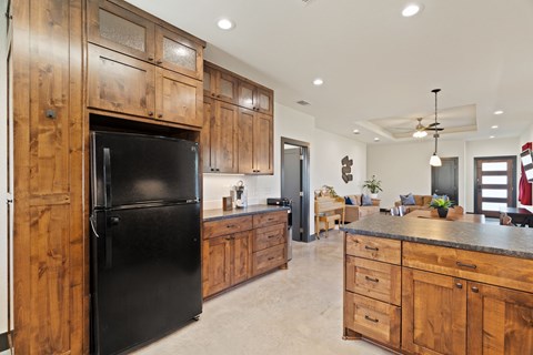 A black refrigerator is in a kitchen with wooden cabinets.
