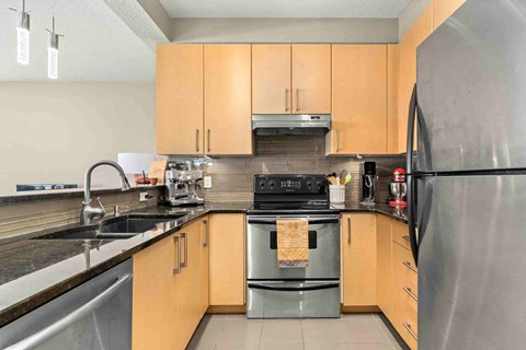 A kitchen with wooden cabinets and a black refrigerator.