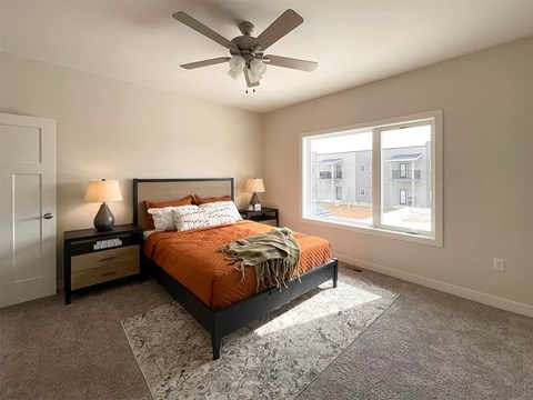 A bedroom with a bed, nightstands, and a ceiling fan.