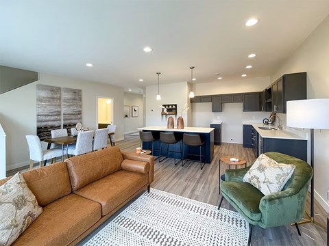A living room with a brown couch and a green armchair.