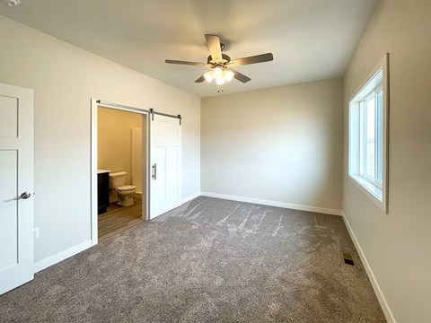 A room with a ceiling fan and carpeted floor.