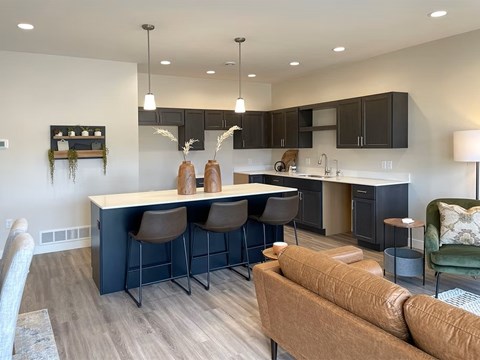 A modern kitchen with a bar area and a brown couch.