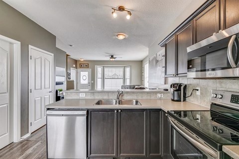 A modern kitchen with dark wood cabinets and stainless steel appliances.