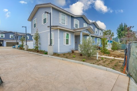 A blue house with a driveway in front.