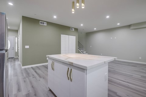 A kitchen with a white countertop and cabinets with gold handles.