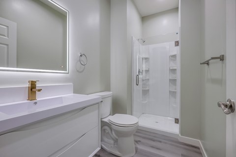 A white bathroom with a toilet, sink, and shower.