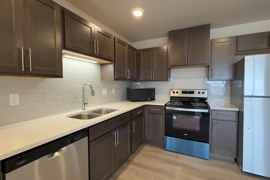 A modern kitchen with dark brown cabinets and stainless steel appliances.