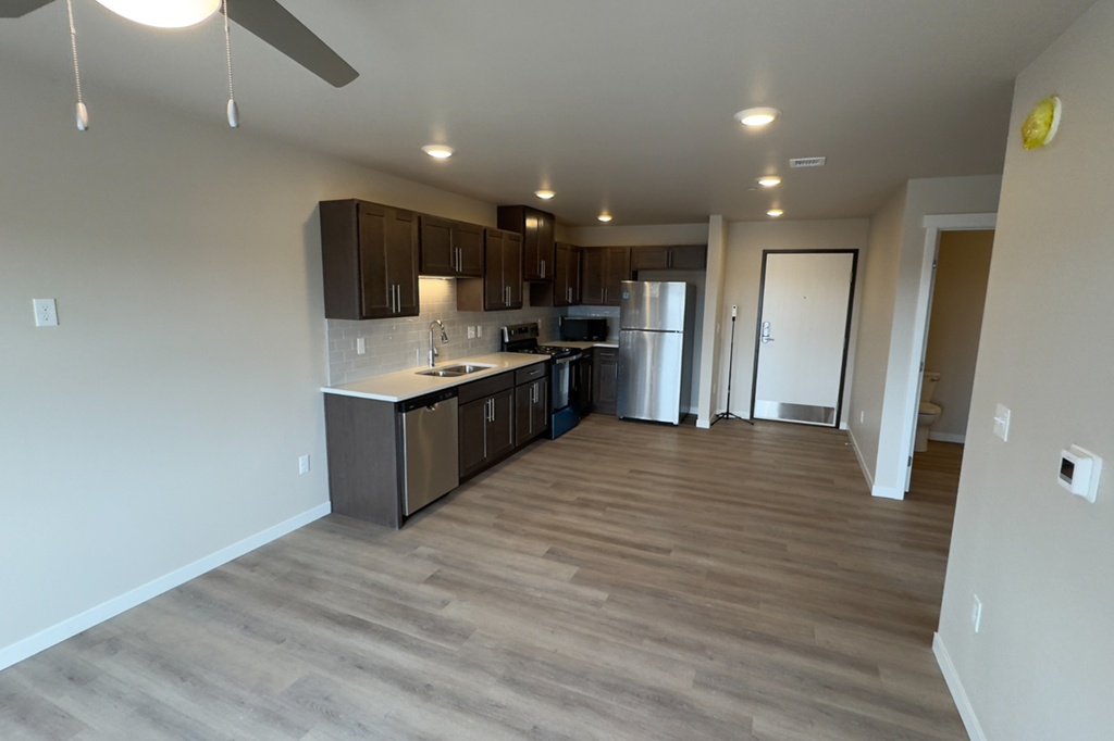 A kitchen with a refrigerator, sink, and cabinets.
