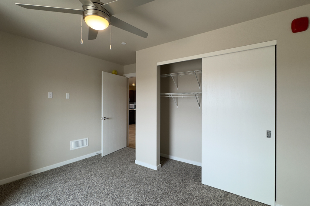 A room with a ceiling fan and a white door.
