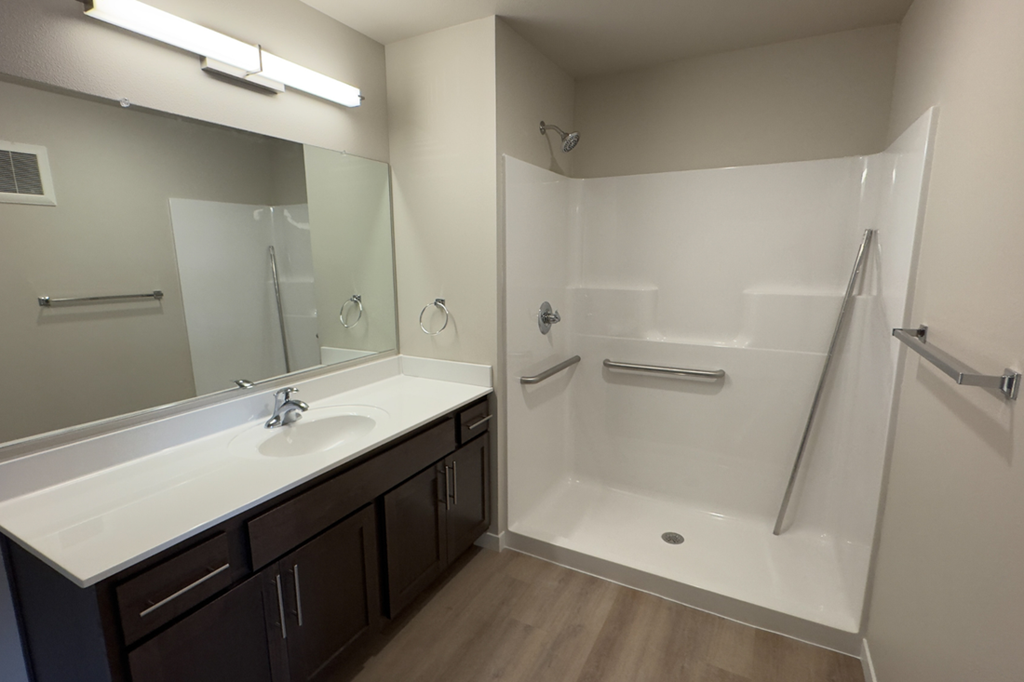 A bathroom with a white sink and a white shower.