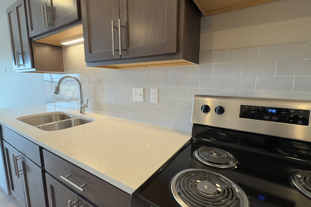 A modern kitchen with a stove top oven and a sink.