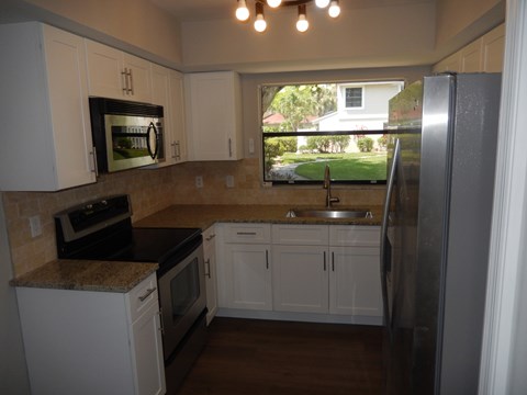 A kitchen with white cabinets and a black countertop.