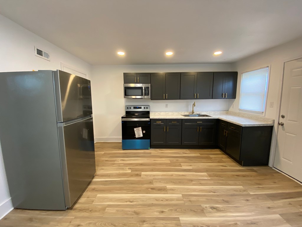 A kitchen with a refrigerator, microwave, oven, and cabinets.