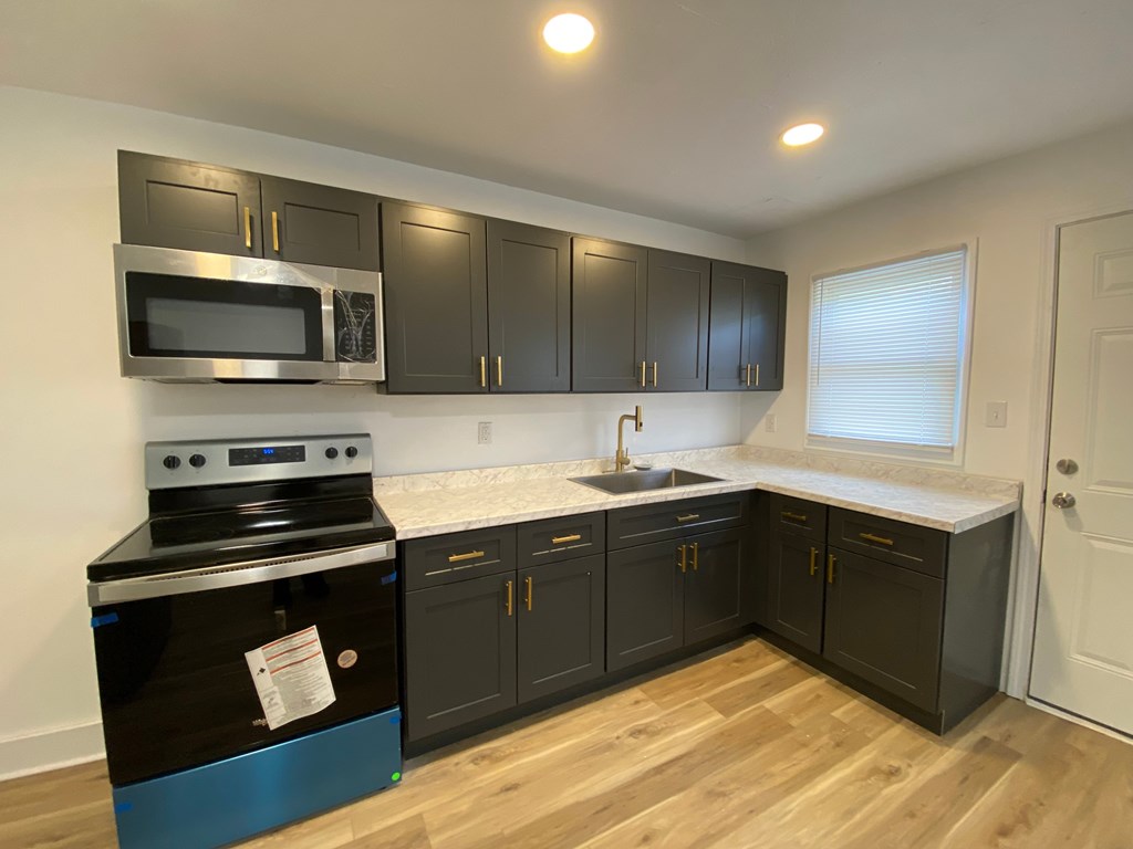 A kitchen with black cabinets and a blue stove top oven.