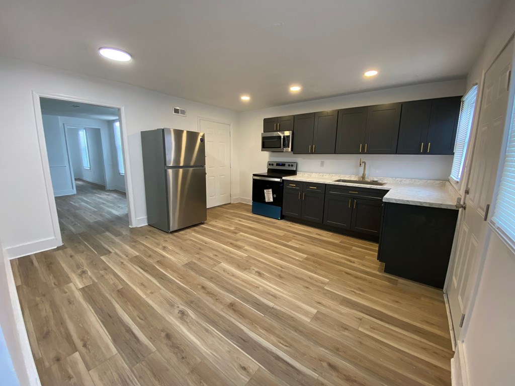 A kitchen with black cabinets and a wooden floor.