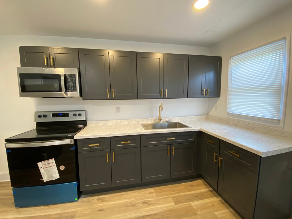 A kitchen with black cabinets and a blue dishwasher.