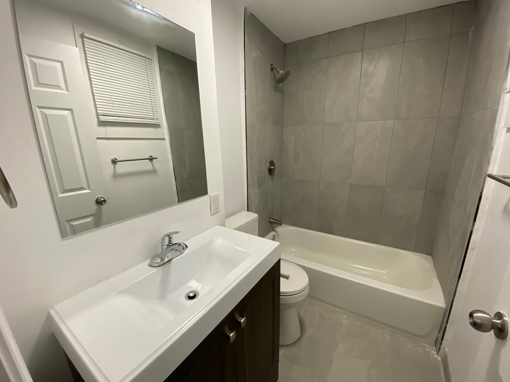 A white sink with a silver faucet is in a bathroom with a white toilet and a white bathtub.