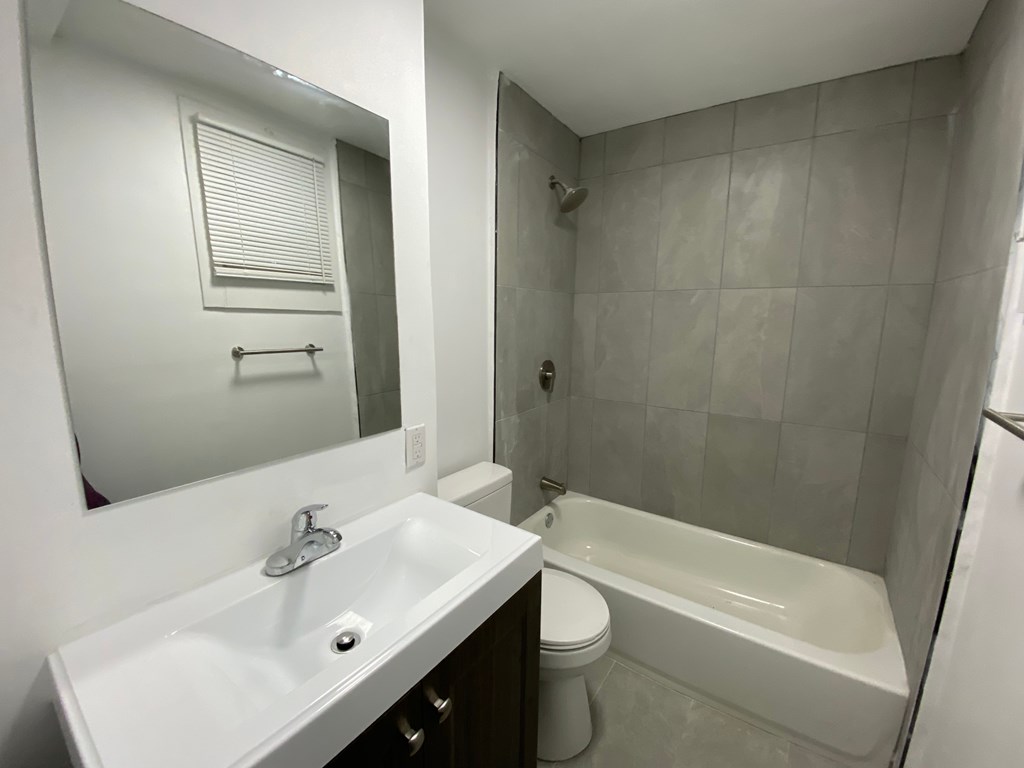 A white sink is in a bathroom with a white toilet and a white tub.
