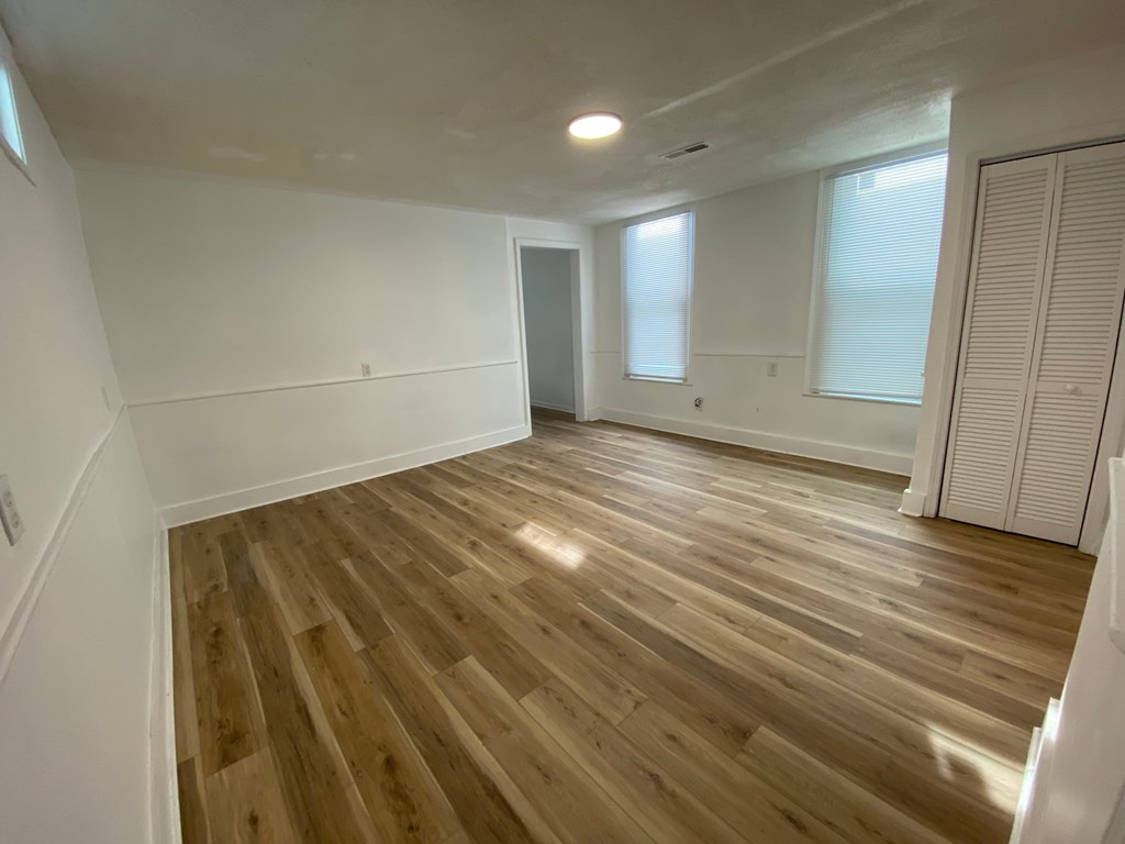 A room with wooden flooring and white walls.