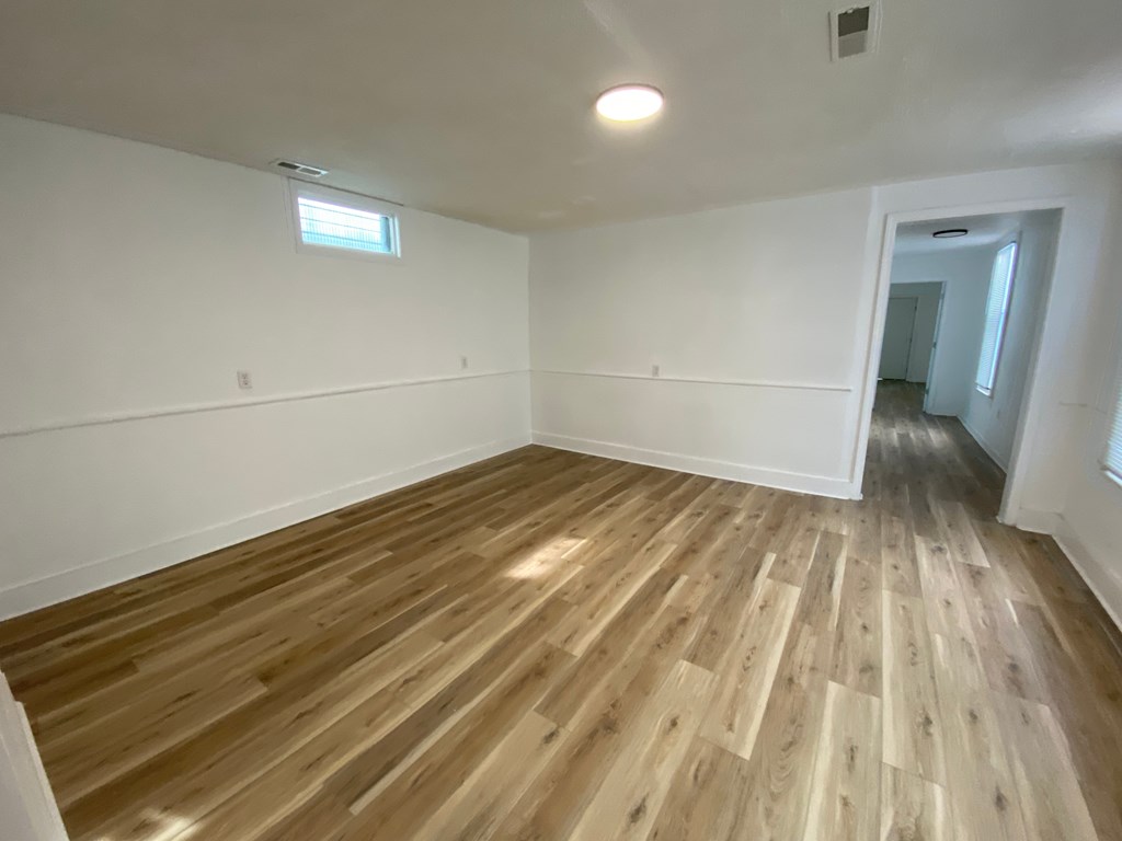 A room with wooden flooring and white walls.