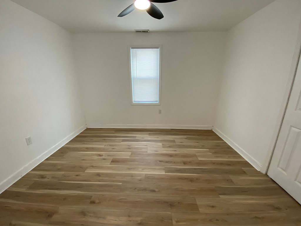 A room with wooden flooring and a ceiling fan.