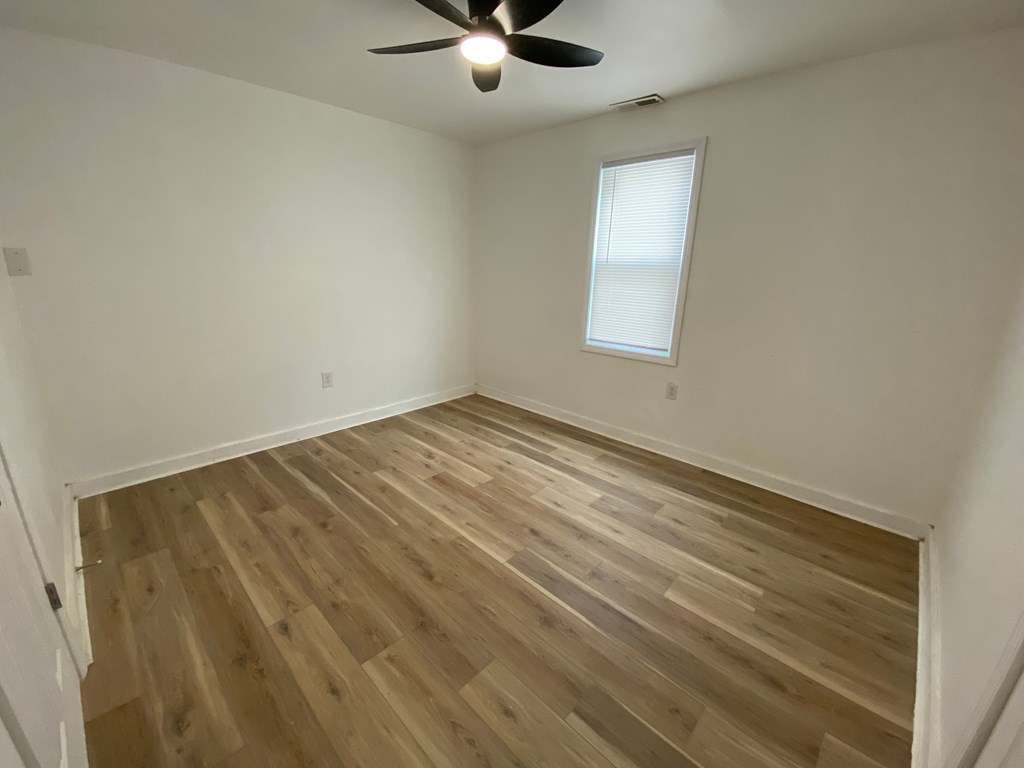 A room with wooden flooring and a ceiling fan.