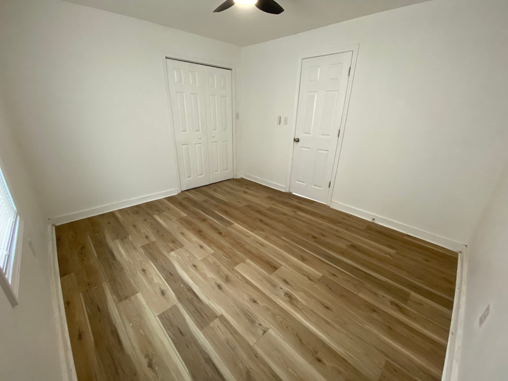 A room with wooden flooring and two white doors.
