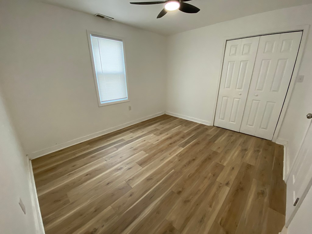 A room with wooden flooring and a ceiling fan.