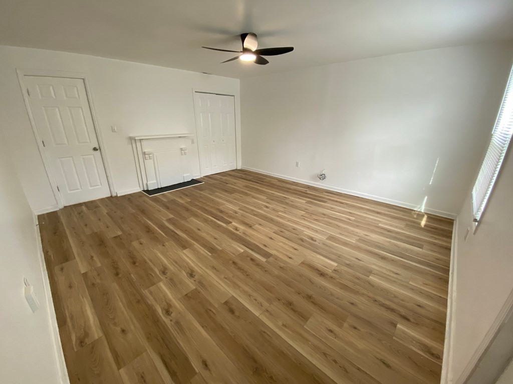 A room with wooden flooring and a ceiling fan.