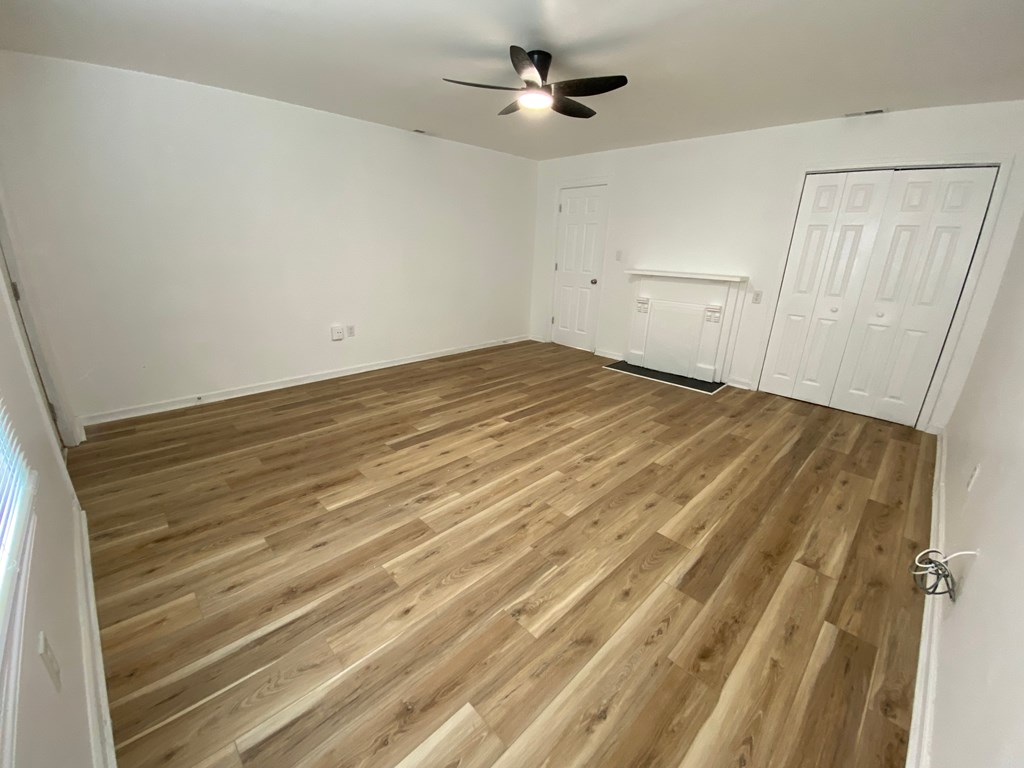 A room with wooden flooring and a ceiling fan.