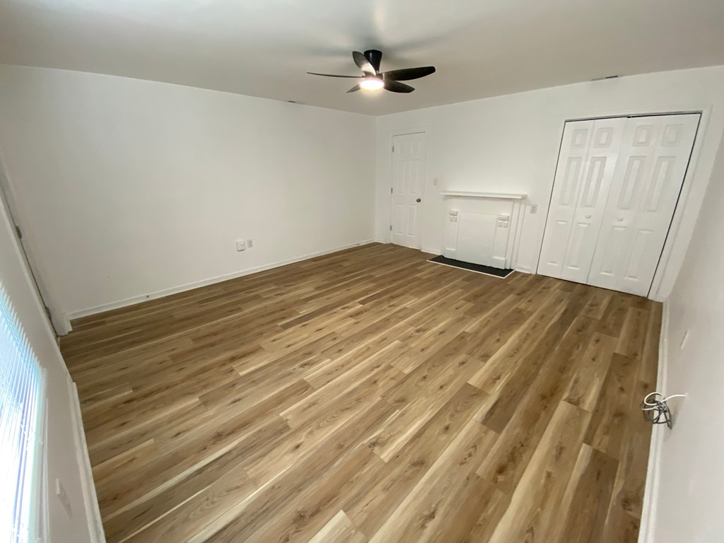 A room with wooden flooring and a ceiling fan.