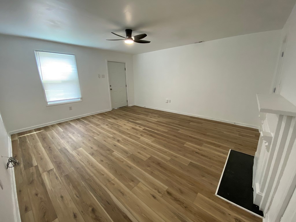 A room with wooden flooring and a ceiling fan.