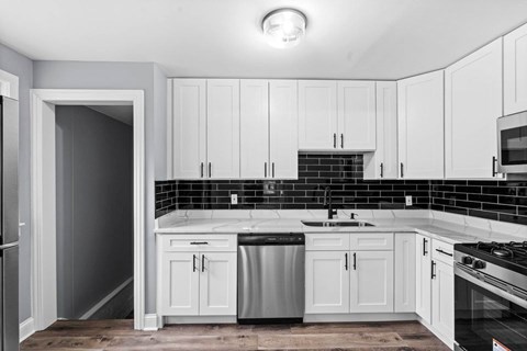 A kitchen with white cabinets and black countertops.
